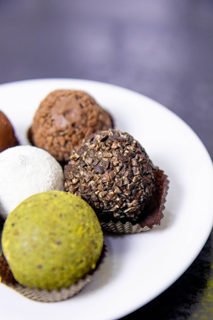 Colorful gourmet truffles displayed on a white plate, perfect for dessert lovers.